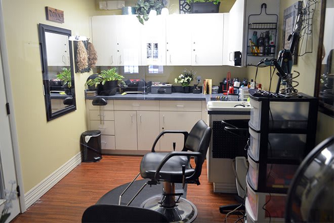 A cozy hair salon with a styling chair, mirror, and various hairdressing equipment.