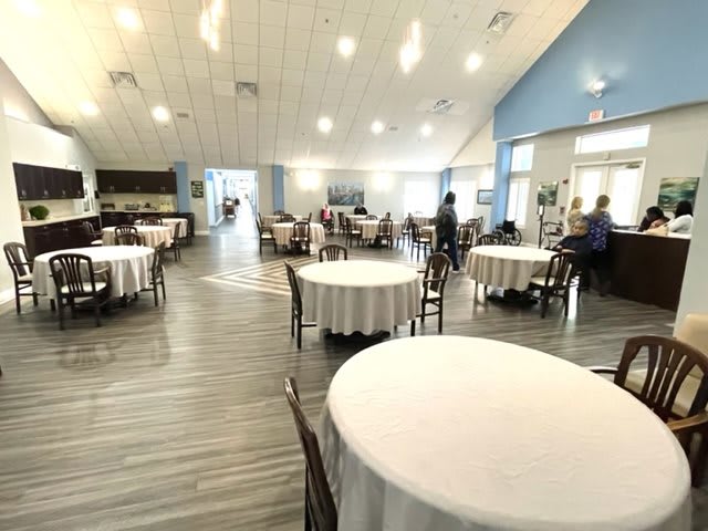 A spacious restaurant interior with round tables and ample natural lighting.