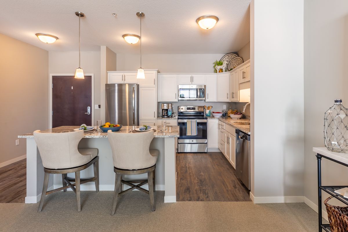 A modern kitchen with stainless steel appliances, a breakfast bar, and stylish lighting.