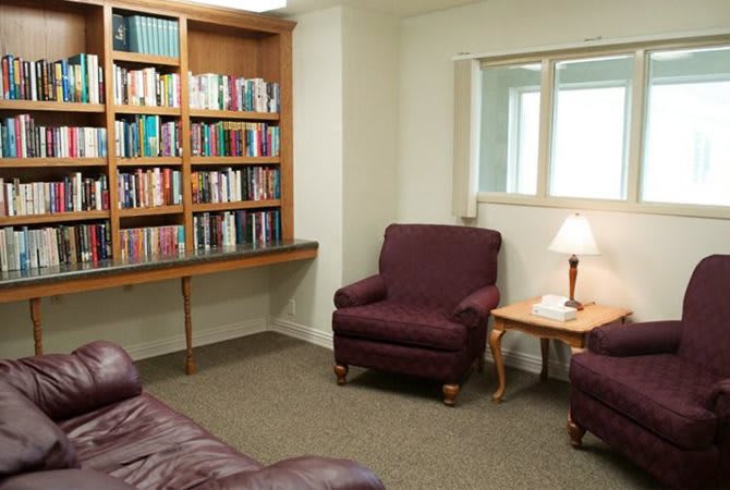 A cozy reading nook featuring a bookshelf and comfortable armchairs.