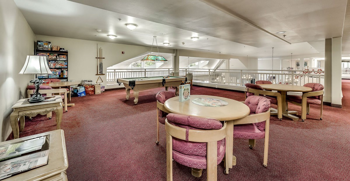 Spacious indoor recreation room featuring pool tables and a card table with comfortable seating.