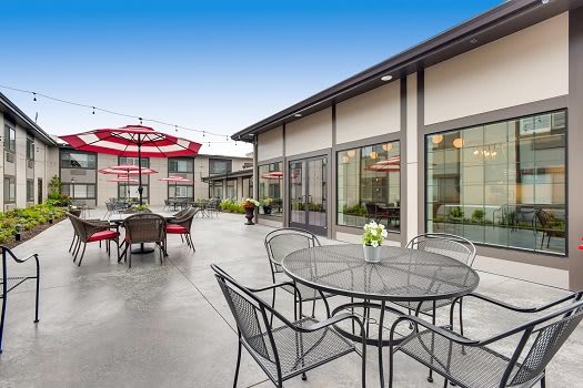 A spacious outdoor patio with tables and chairs under a clear blue sky.