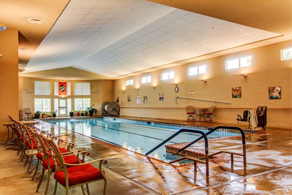 An inviting indoor swimming pool area with chairs and ample natural light.
