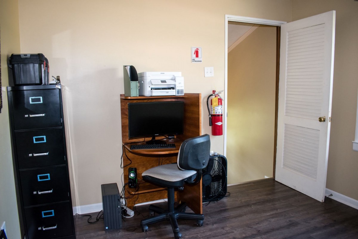A small office setup with a computer desk, chair, and printer.