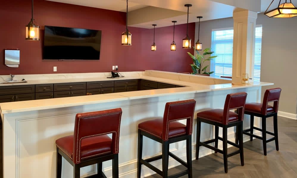A modern bar area with red stools and pendant lighting.