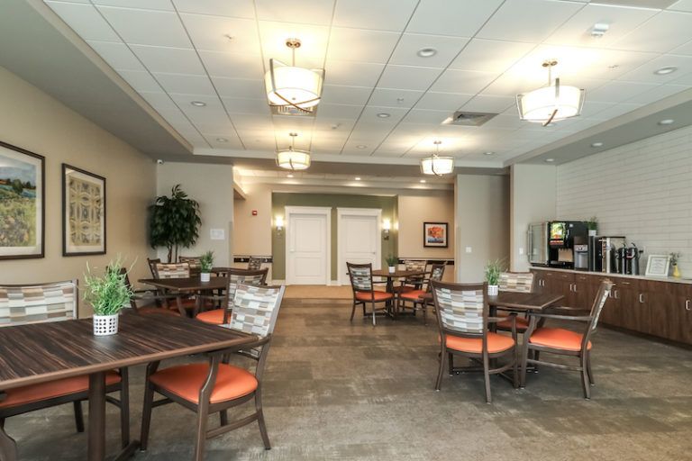 A modern dining area with neatly arranged tables and chairs, illuminated by stylish ceiling lights.