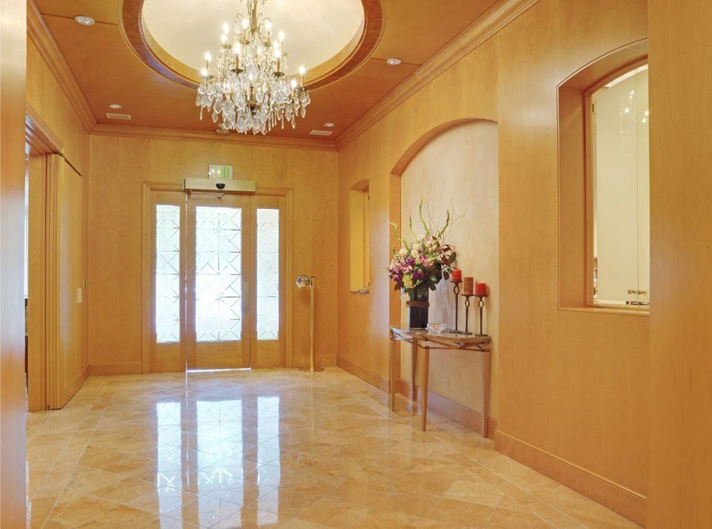 A luxurious lobby featuring a grand chandelier and a marble floor, with floral decorations enhancing the elegant entrance.