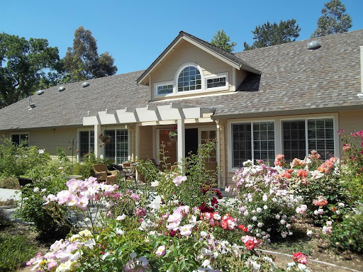 A beautiful home surrounded by vibrant rose bushes on a sunny day.