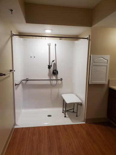 An accessible shower space featuring a bench and grab bars for safety.