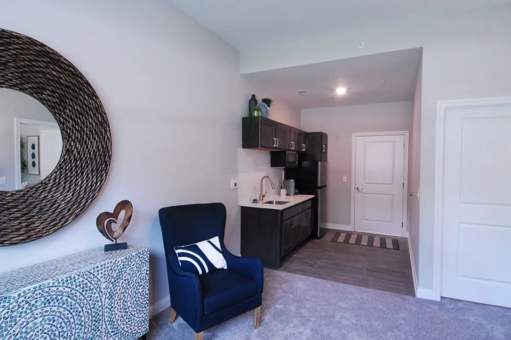 A cozy and modern apartment living area with a kitchenette, featuring minimalist decor and comfortable seating.