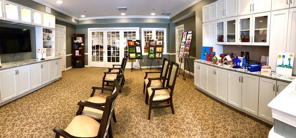 An art exhibit room with chairs arranged facing various paintings displayed on easels.
