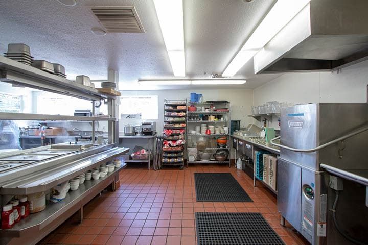 A clean and organized commercial kitchen with stainless steel appliances and shelving.