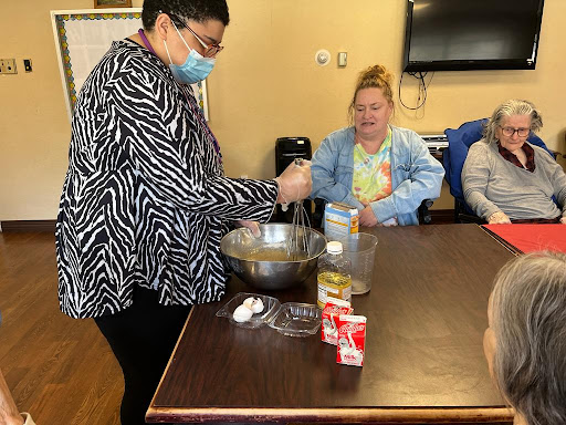 A group cooking session where a participant demonstrates mixing ingredients while others observe.