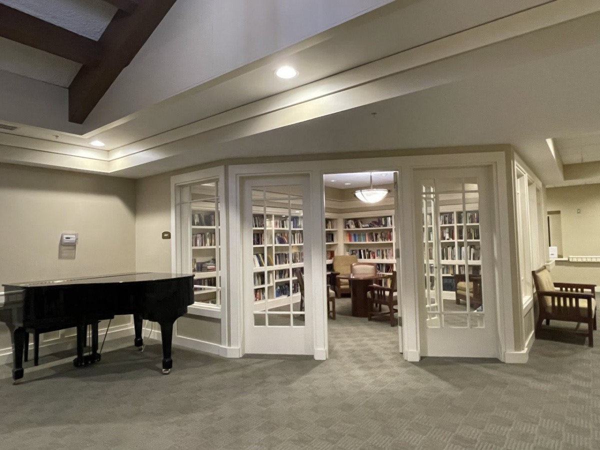 A cozy library with a grand piano and bookshelves.