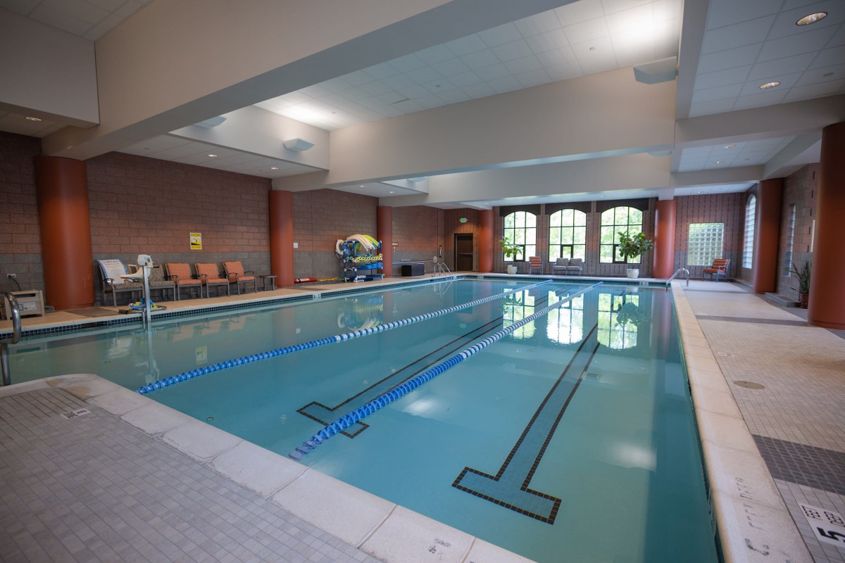 An indoor swimming pool with clean, clear water and comfortable seating areas.