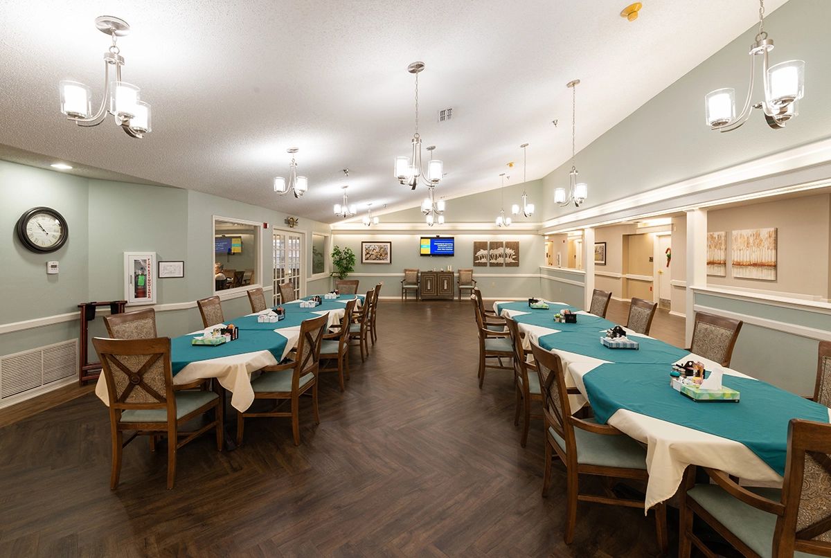 A spacious dining area with multiple tables and chairs, featuring elegant lighting and wooden flooring.