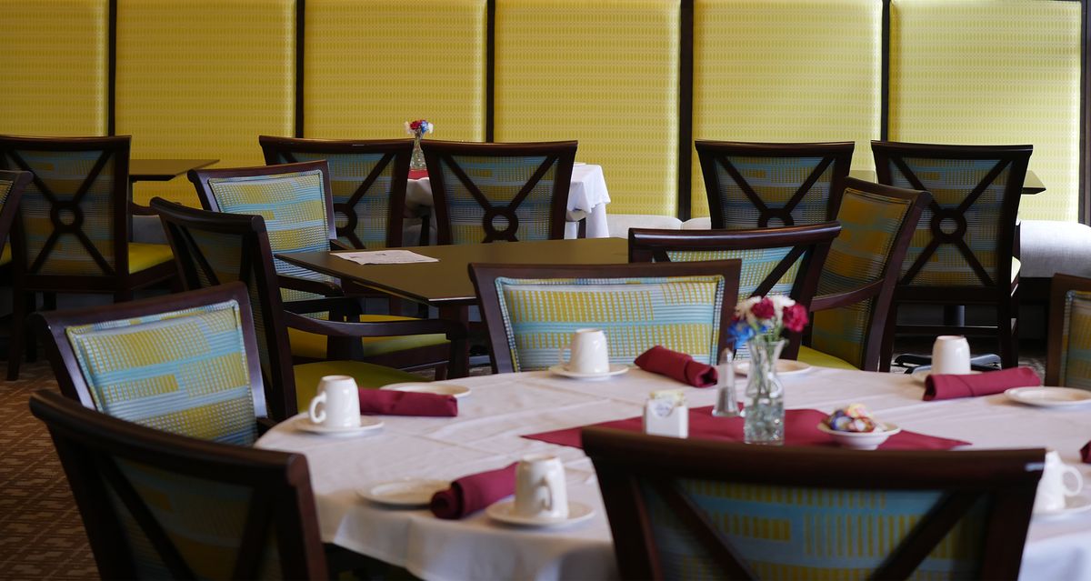 A neatly set dining area with tables and chairs arranged in a restaurant.