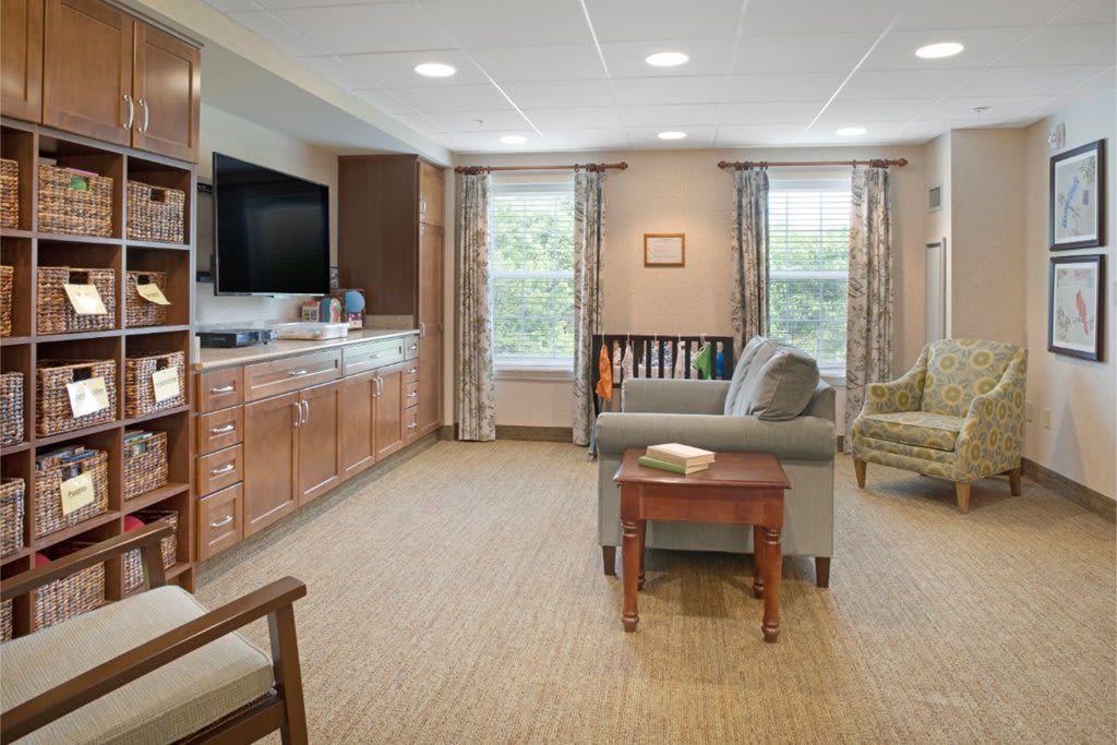 A cozy living room with modern furnishings, including a large television, bookshelves, and comfortable seating.