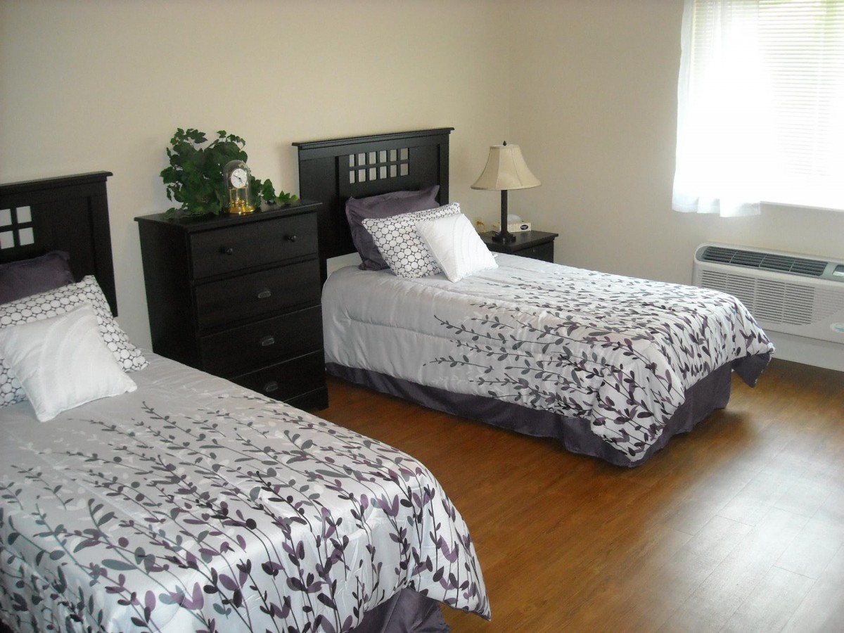 A cozy bedroom with two single beds, equipped with matching bedding and a neatly arranged dresser.