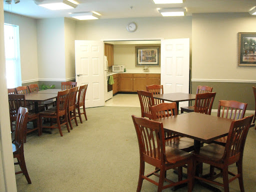 A cozy dining area featuring wooden tables and chairs, leading to a kitchen space.
