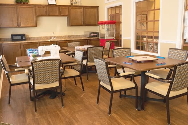 A cozy dining area with several tables and chairs, featuring a popcorn machine and wooden cabinetry.