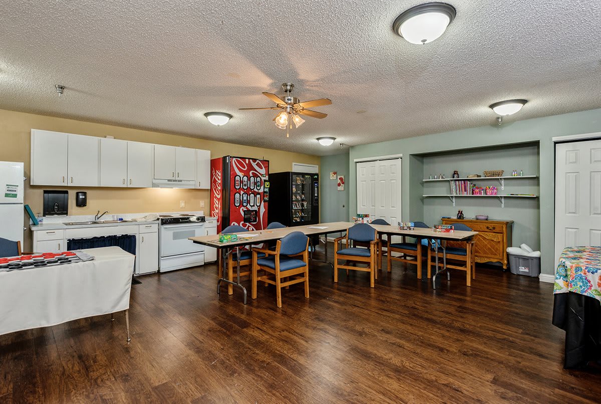 A spacious kitchen and dining area featuring wooden flooring, a vending machine, and ample seating.