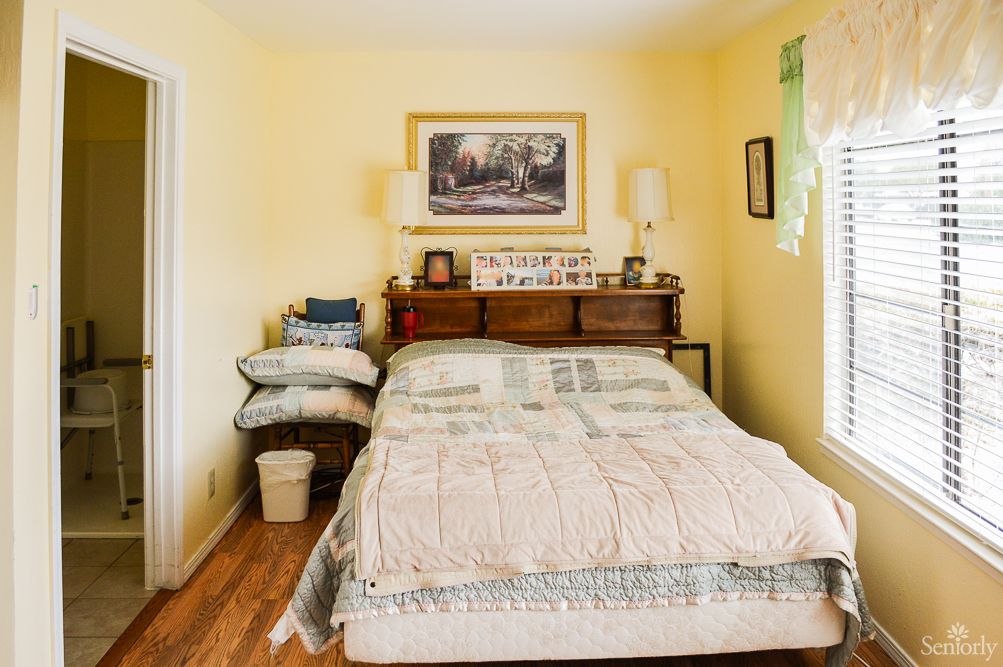 A cozy bedroom with a bed, wooden furniture, and decorative elements on the wall.