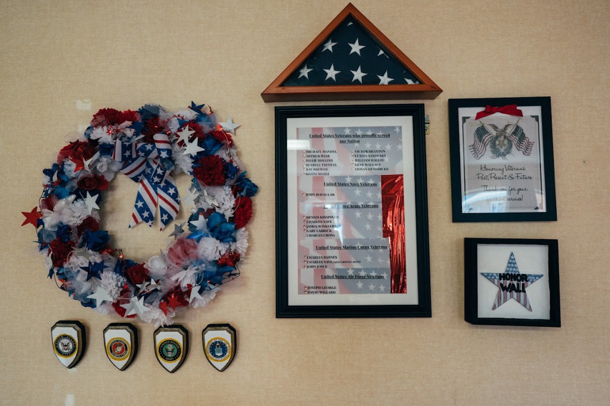 A display featuring patriotic decorations, including a folded American flag, plaques, and a festive wreath on the wall.