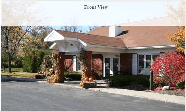 Front view of a building entrance with autumn decorations and pumpkins.