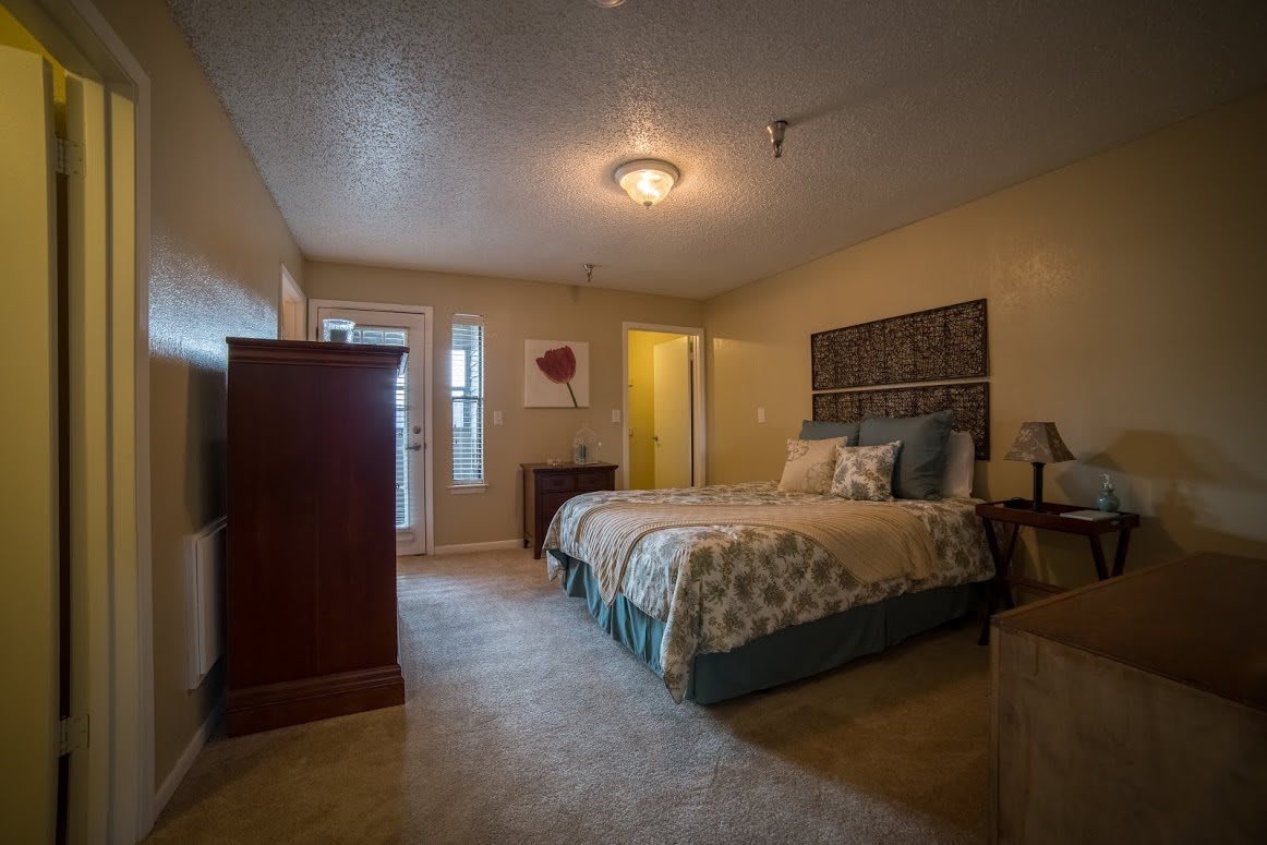 A cozy bedroom with a large bed, dresser, and soft lighting.