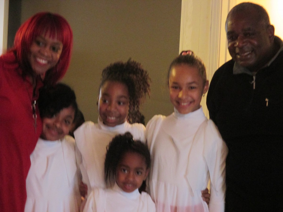 A family group photo with several children and two adults, all smiling.