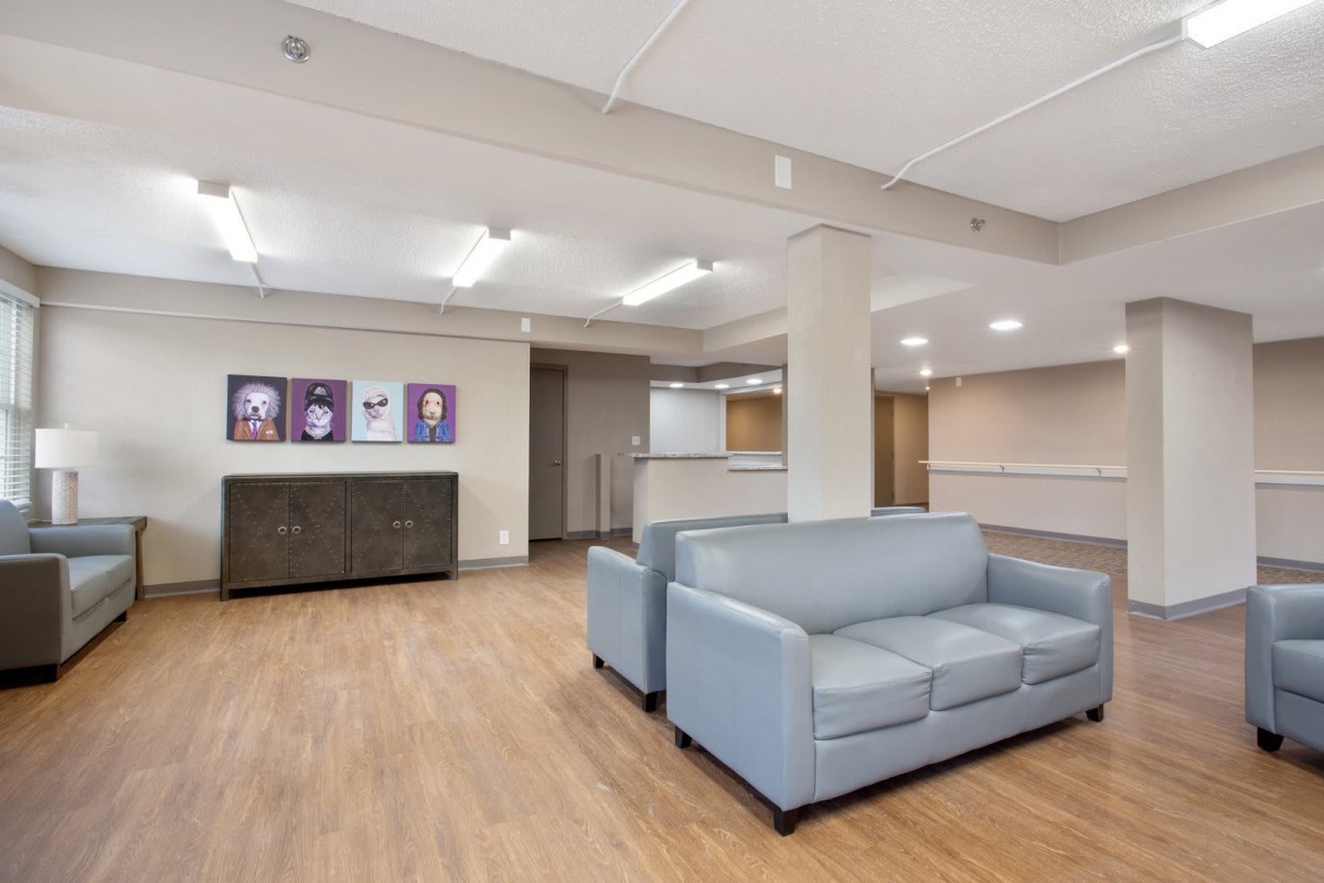 A modern lobby area featuring light gray sofas, wood flooring, and contemporary artwork on the walls.