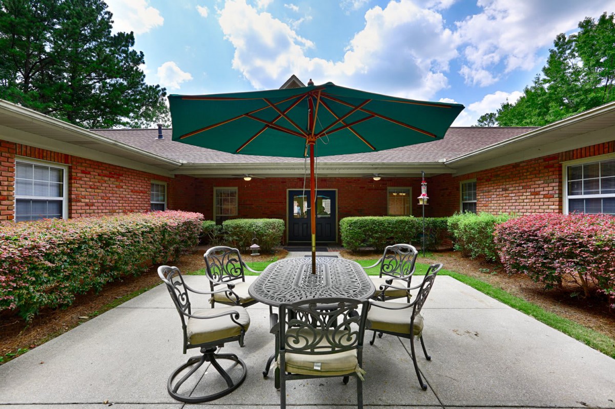 A tranquil courtyard featuring a patio set with an umbrella, enclosed by a brick building.
