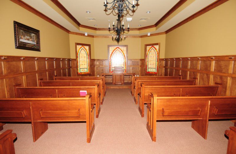 A small chapel with wooden pews and stained glass windows.