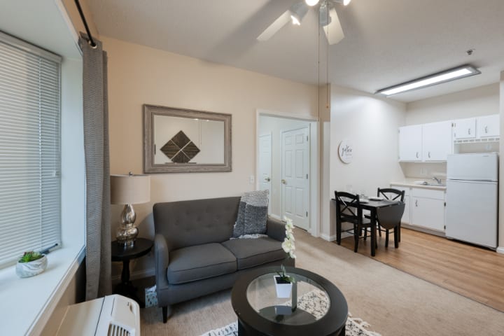 A modern living room with a comfortable sofa and a dining area in the background.