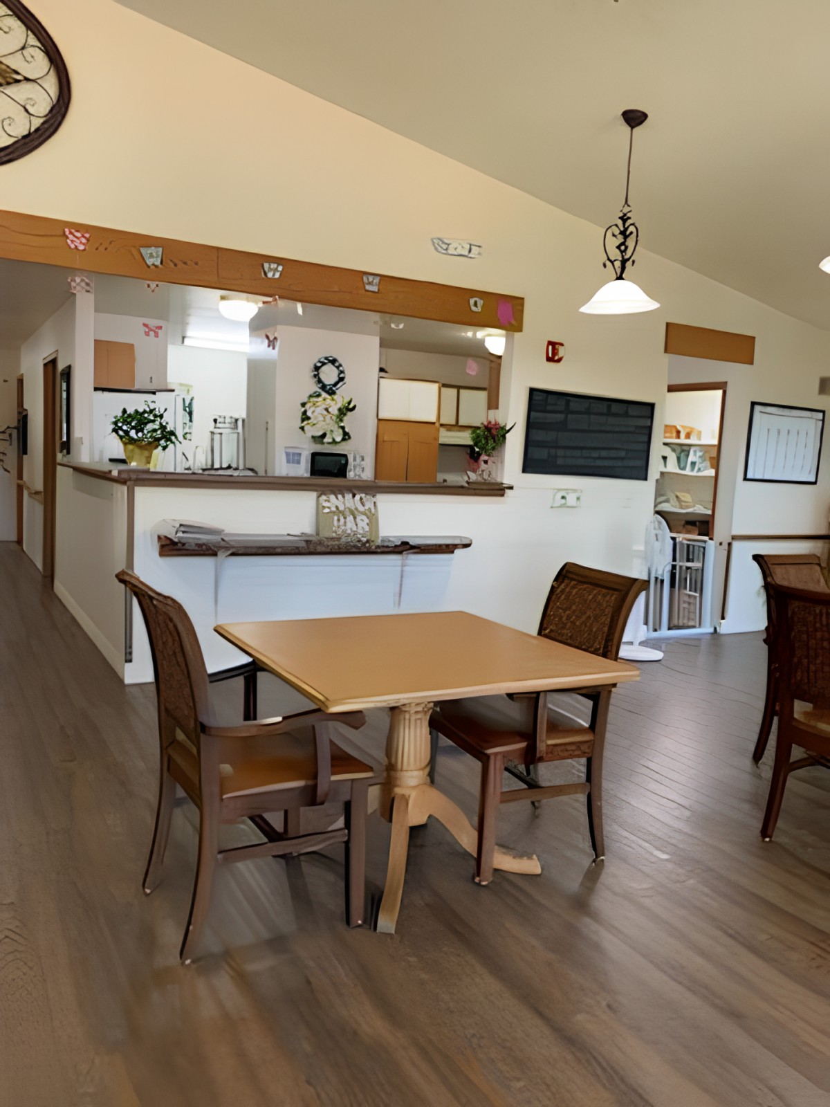 A cozy dining area with wooden tables and chairs, adjacent to a kitchen space.