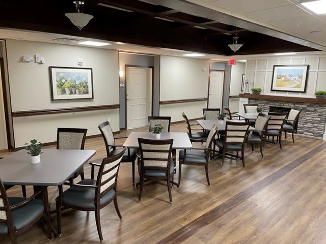 A modern dining area with neatly arranged tables and chairs, featuring wood flooring and decorative artwork on the walls.
