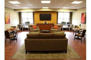 A modern lounge area with comfortable seating, a large TV, and ample natural light.