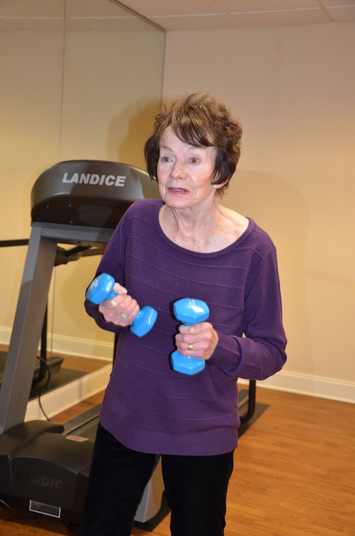 An individual exercising with dumbbells next to a treadmill.