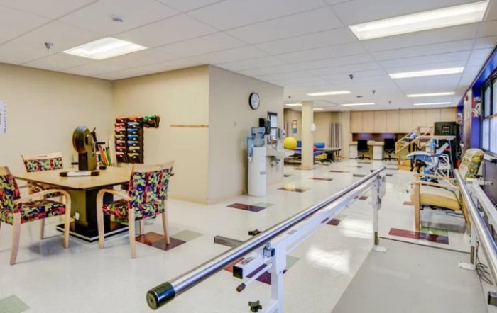 A physical therapy room equipped with parallel bars and various exercise tools.