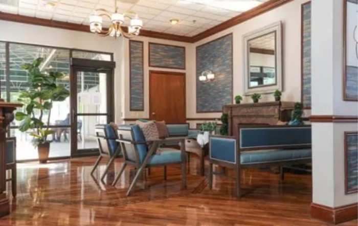 A well-furnished waiting area with blue upholstered chairs and a wooden table.