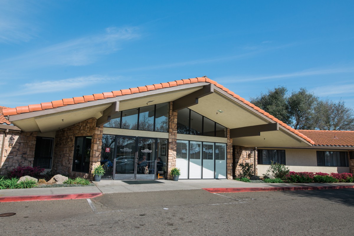 A modern building with a distinct triangular roof design, featuring large glass doors and windows, under a clear blue sky.