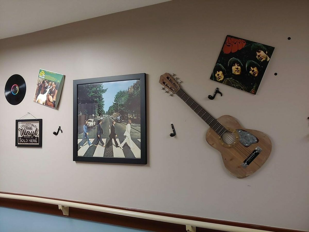 A wall decorated with music-themed artwork, including a guitar, album covers, and musical notes.