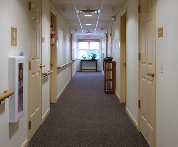 A well-lit hallway with carpeted flooring and doors on either side.