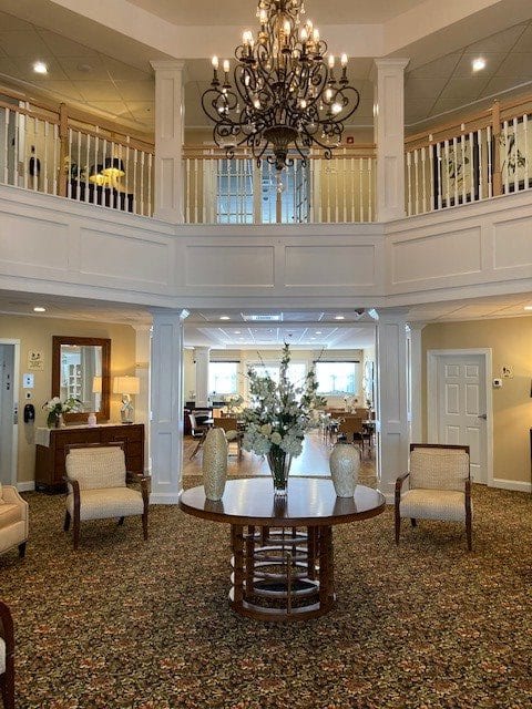 A spacious and elegantly decorated lobby with a chandelier, comfortable seating, and a staircase.