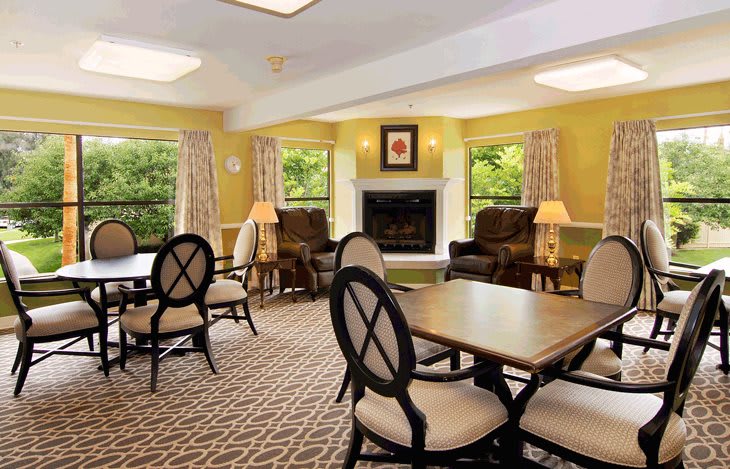 A cozy living room with tables, chairs, and a fireplace.