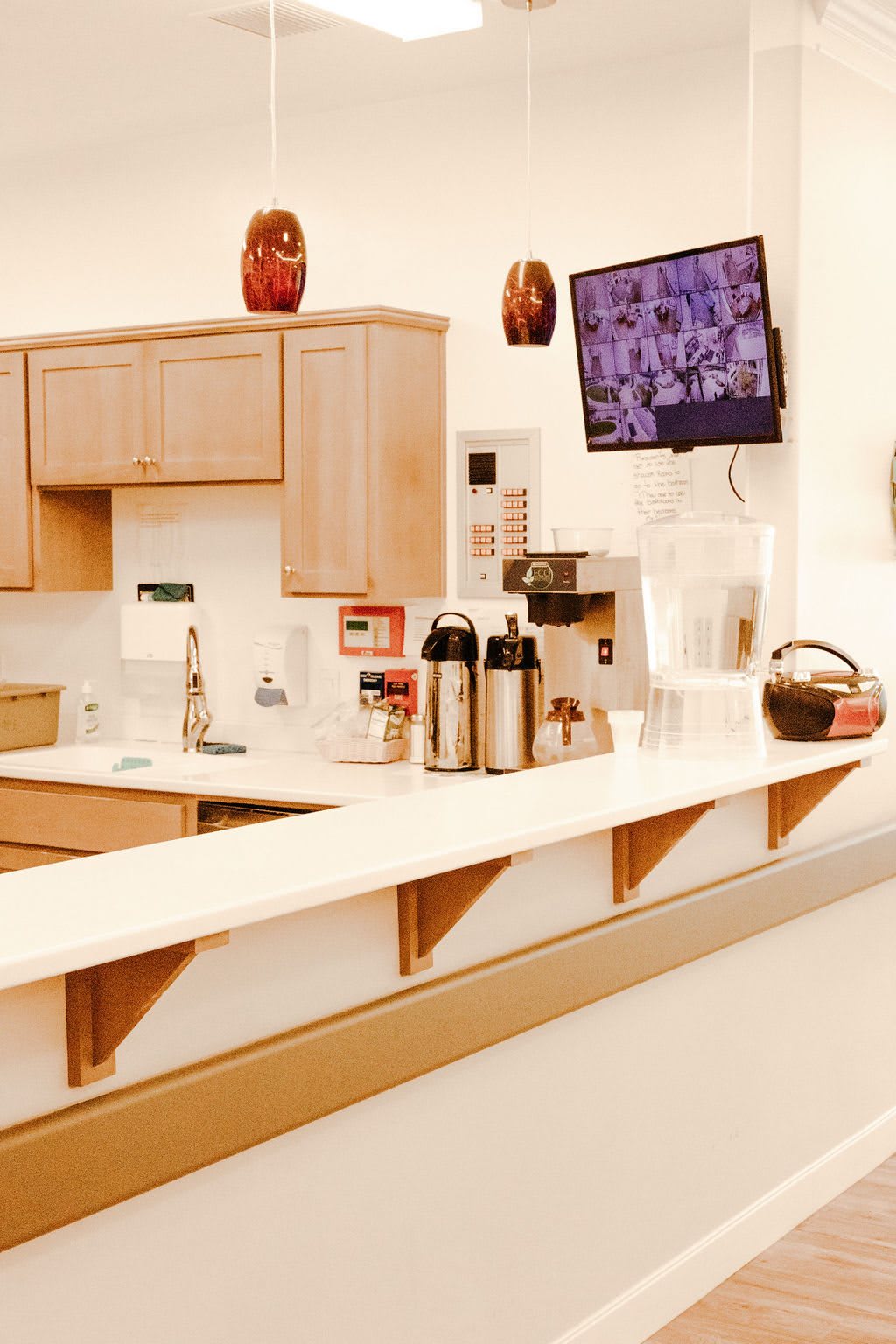 A kitchen area featuring a counter with a coffee station and wall-mounted television.