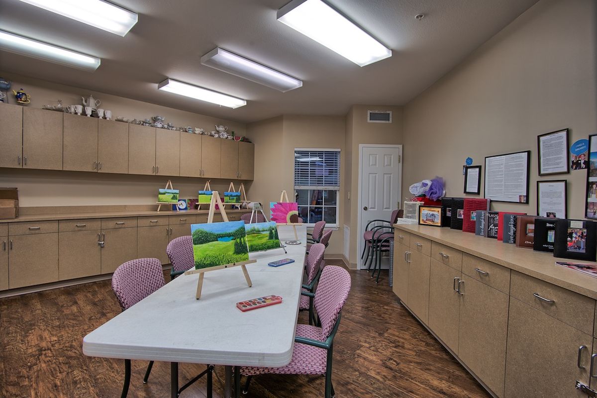 An art classroom with tables and chairs, equipped with various art supplies.