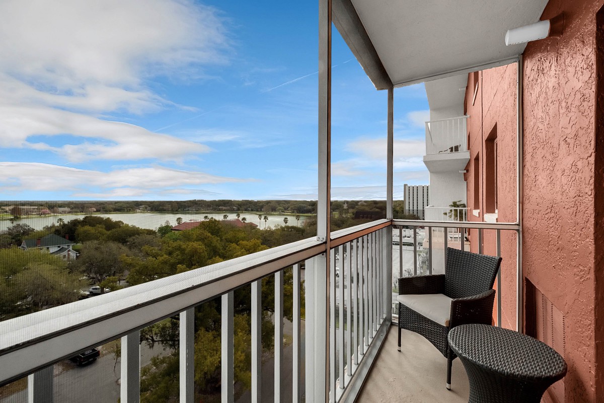 A balcony with outdoor seating overlooking a scenic view and clear sky.