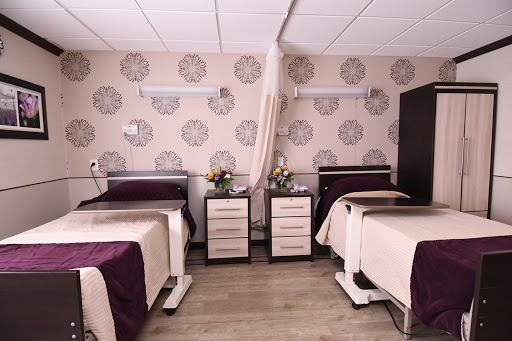 A well-designed hospital room featuring two patient beds, modern furniture, and tasteful floral decorations.